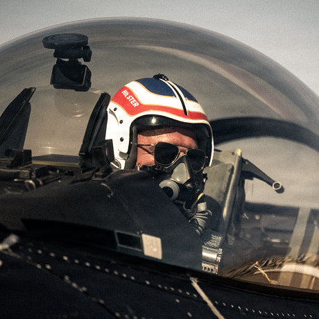 Pilot wearing aviator sunglasses inside a military aircraft cockpit.